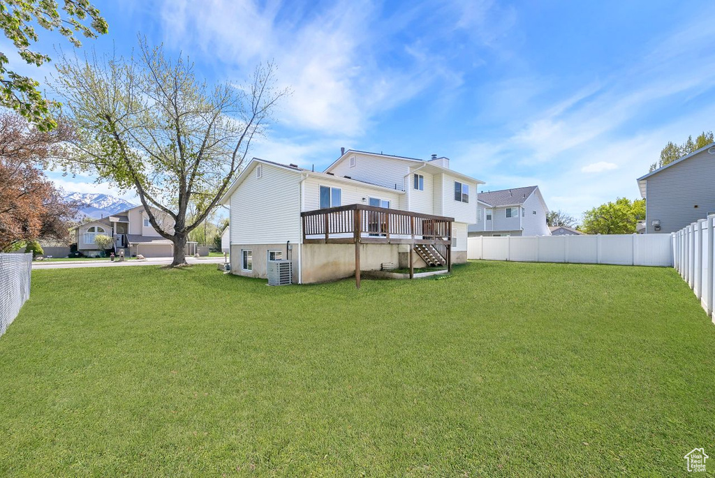 Rear view of property featuring a fenced backyard, a yard, stairway, central air condition unit, and a wooden deck