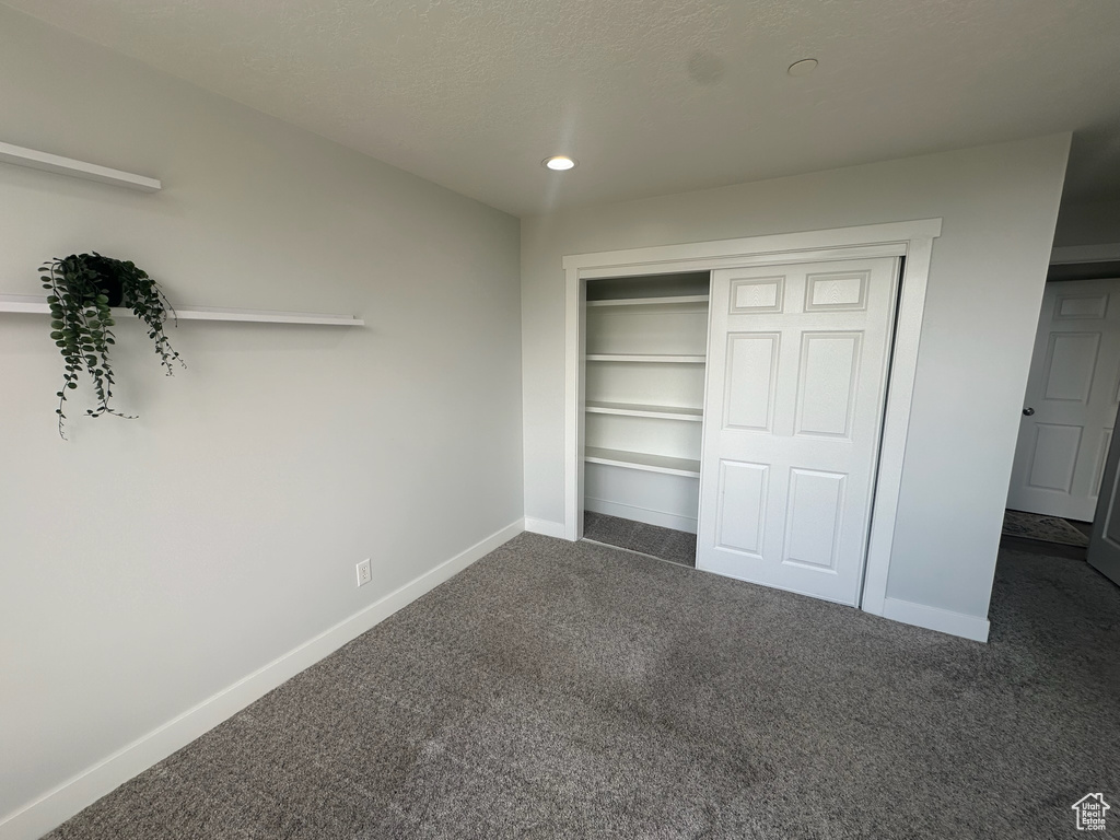 Unfurnished bedroom featuring recessed lighting, dark colored carpet, a closet, and baseboards