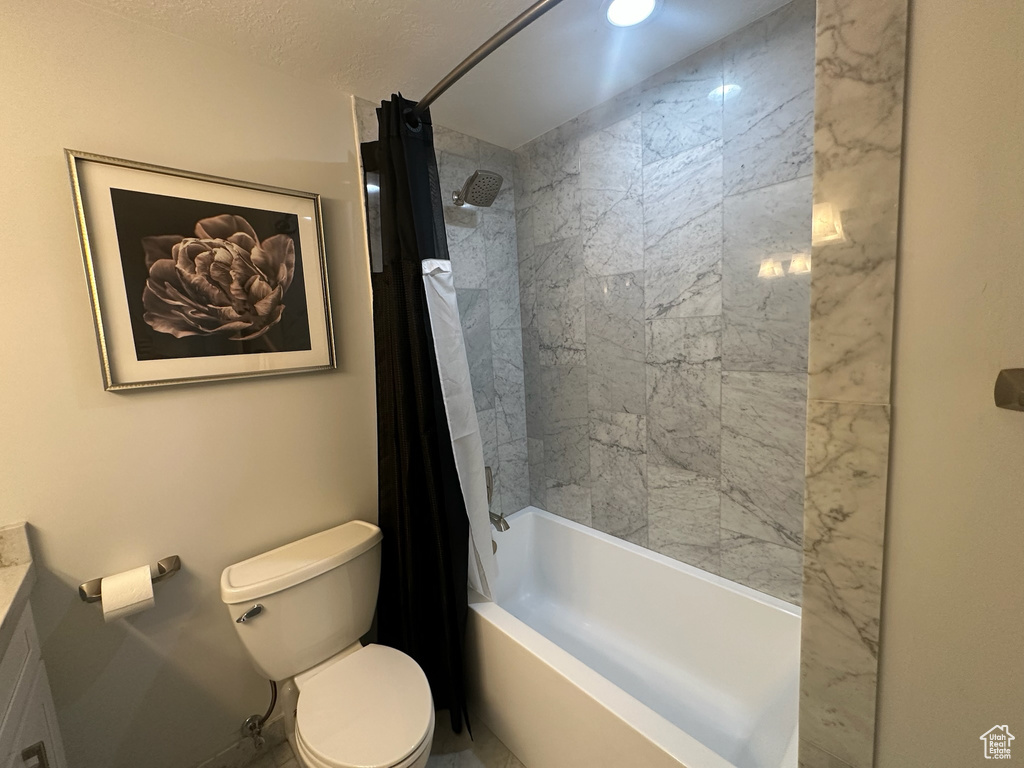 Bathroom featuring baseboards, shower / tub combo with curtain, toilet, and vanity