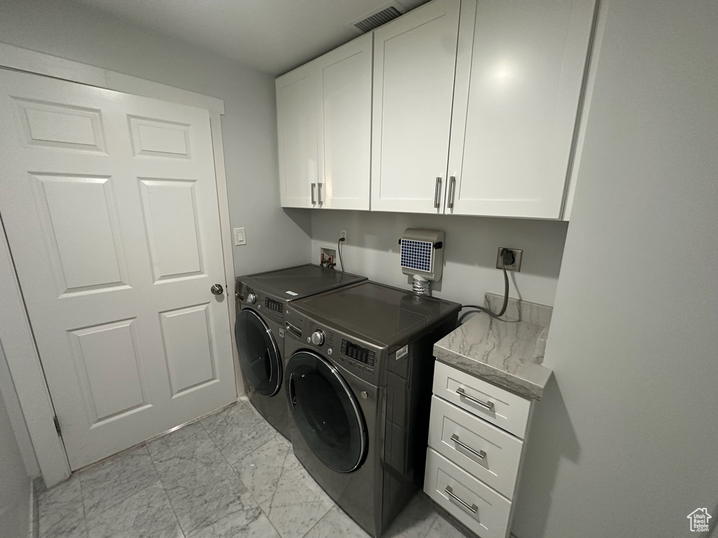 Clothes washing area featuring marble finish floor, cabinet space, visible vents, and independent washer and dryer
