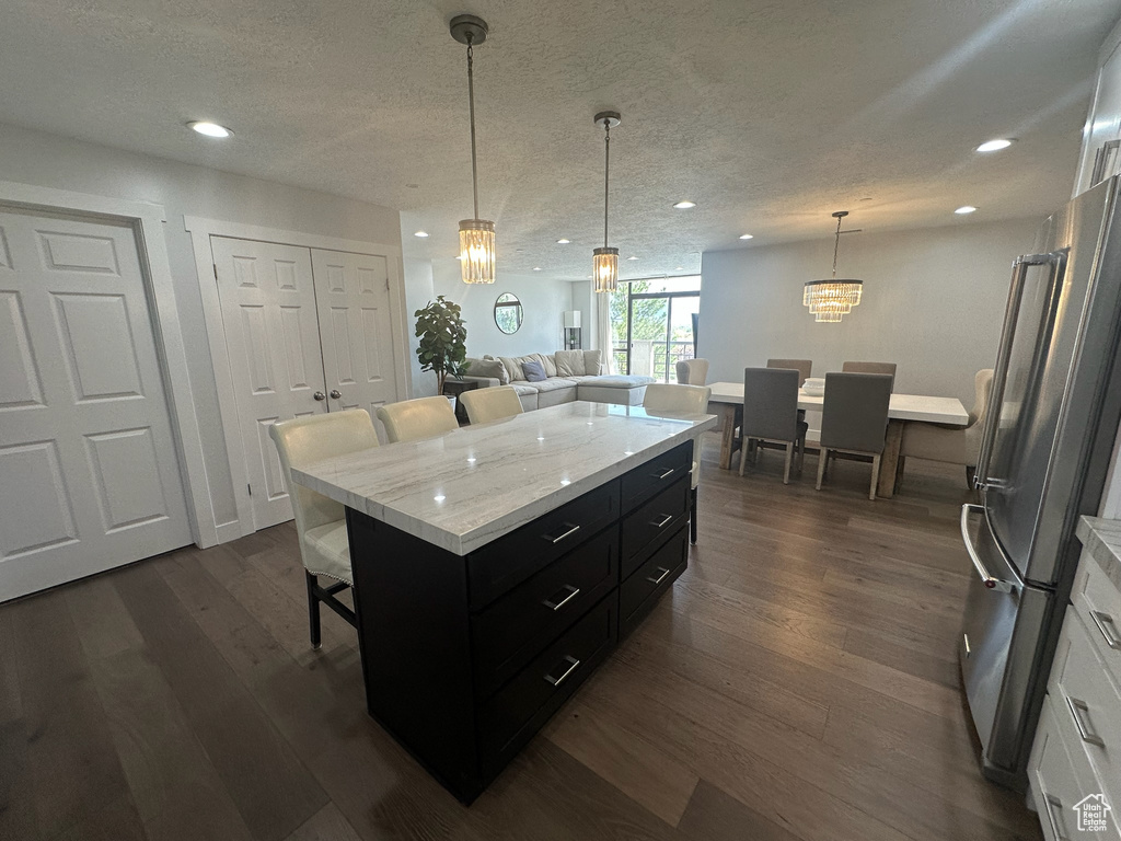 Kitchen with white cabinetry, dark cabinetry, freestanding refrigerator, a breakfast bar area, and a notable chandelier