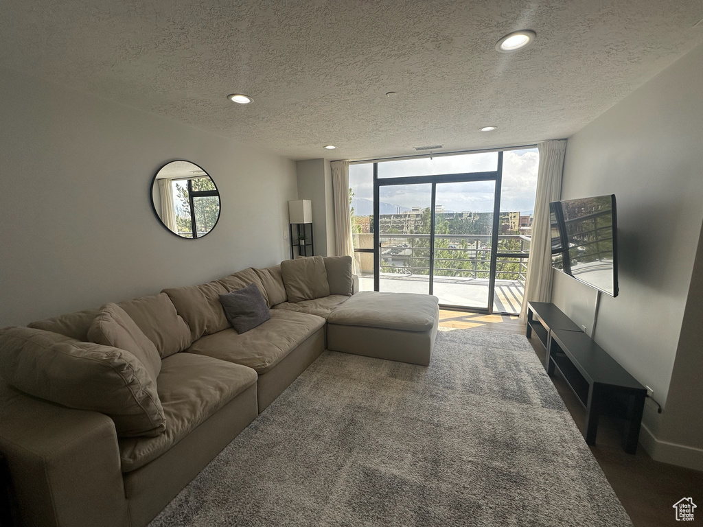 Living room with floor to ceiling windows, a textured ceiling, and recessed lighting