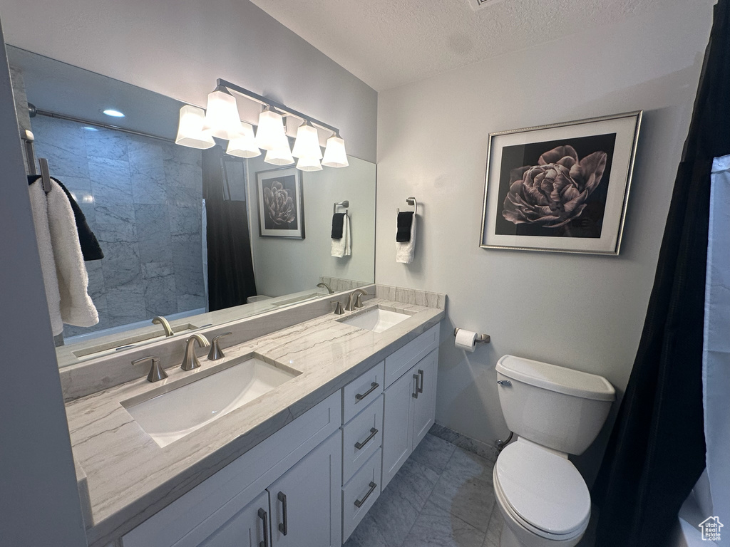 Bathroom with a textured ceiling, toilet, and a sink
