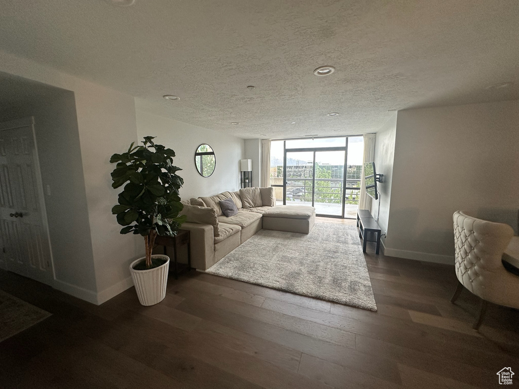 Living area with baseboards, a textured ceiling, and dark wood-style flooring