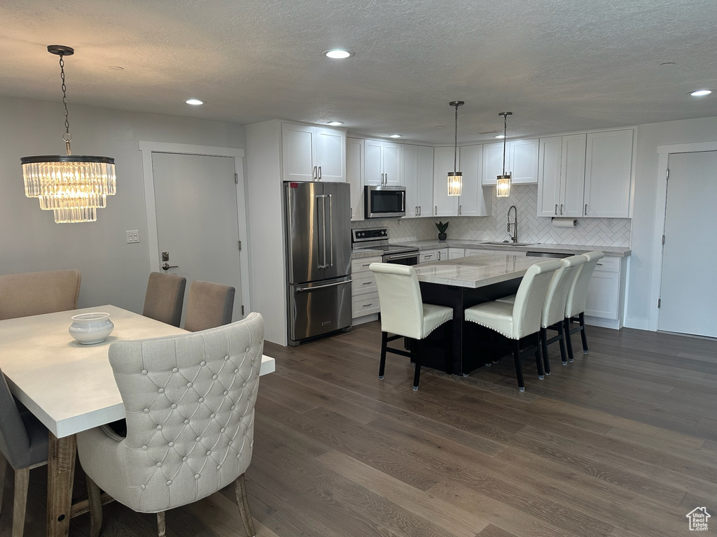 Dining space featuring a chandelier, a textured ceiling, dark wood-style flooring, and recessed lighting