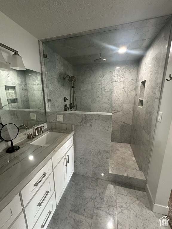 Bathroom with walk in shower, a textured ceiling, marble finish floor, and vanity
