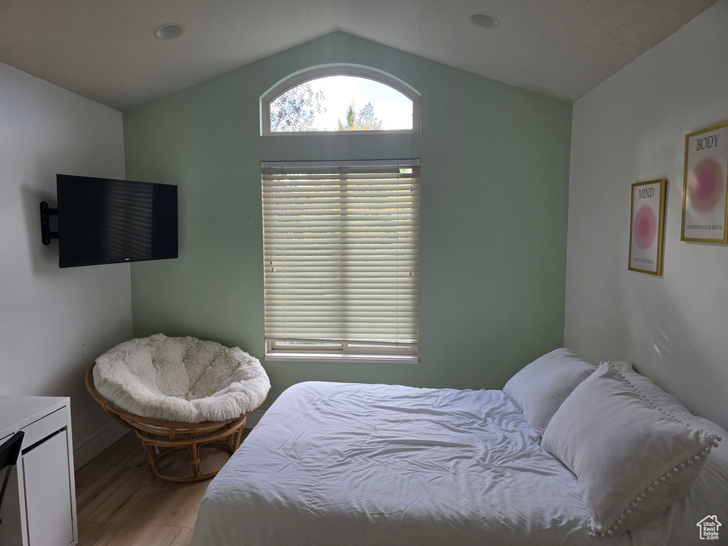 Bedroom with baseboards, light wood-style flooring, and vaulted ceiling