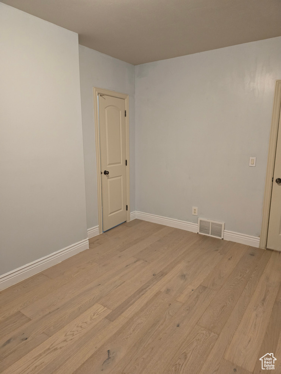 Empty room with visible vents, baseboards, and light wood-type flooring