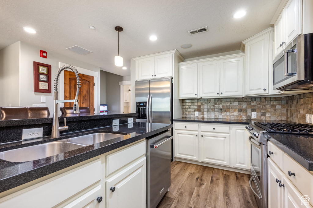Kitchen featuring appliances with stainless steel finishes, light wood-style flooring, white cabinets, and recessed lighting