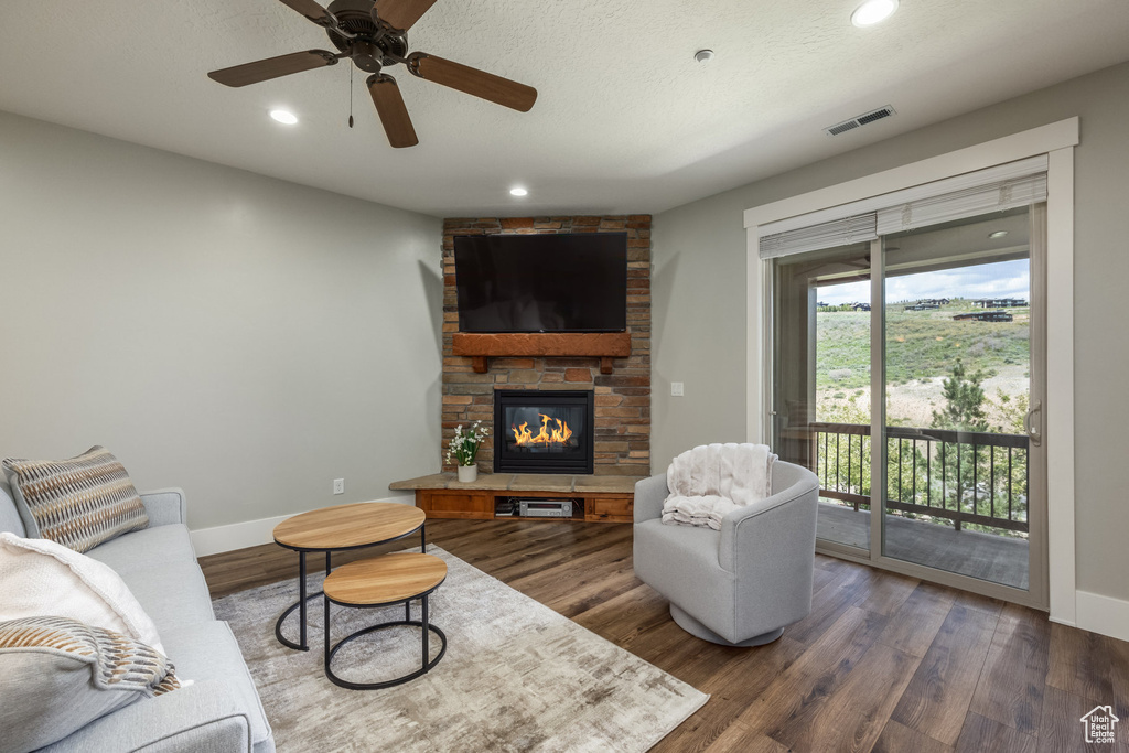 Living room featuring a stone fireplace, wood finished floors, recessed lighting, and ceiling fan