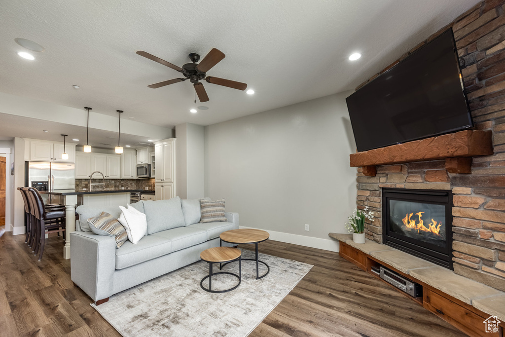 Living area with ceiling fan, dark wood finished floors, a fireplace, and recessed lighting
