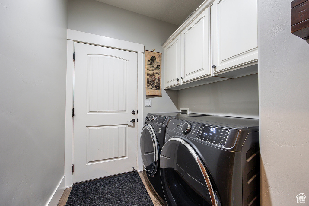 Laundry area featuring separate washer and dryer, cabinet space, and dark wood-style floors