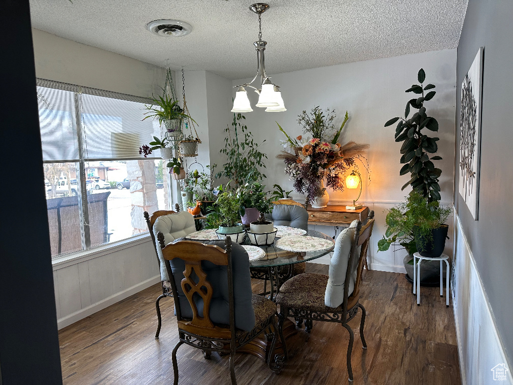 Dining space featuring a textured ceiling, wood finished floors, visible vents, and baseboards