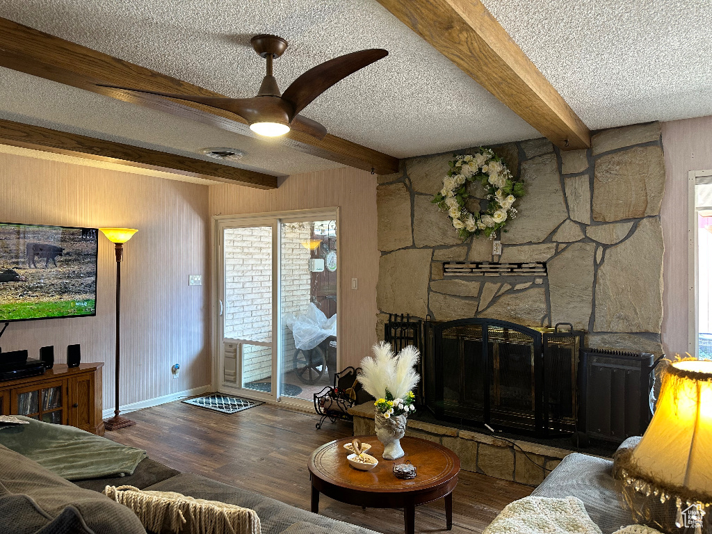Living area with beamed ceiling, wooden walls, a textured ceiling, and ceiling fan