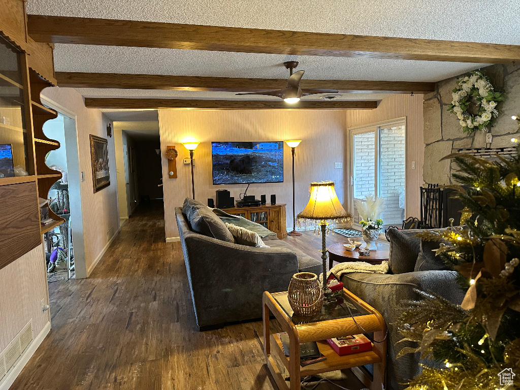 Living area with beamed ceiling, wood walls, baseboards, wood finished floors, and a ceiling fan