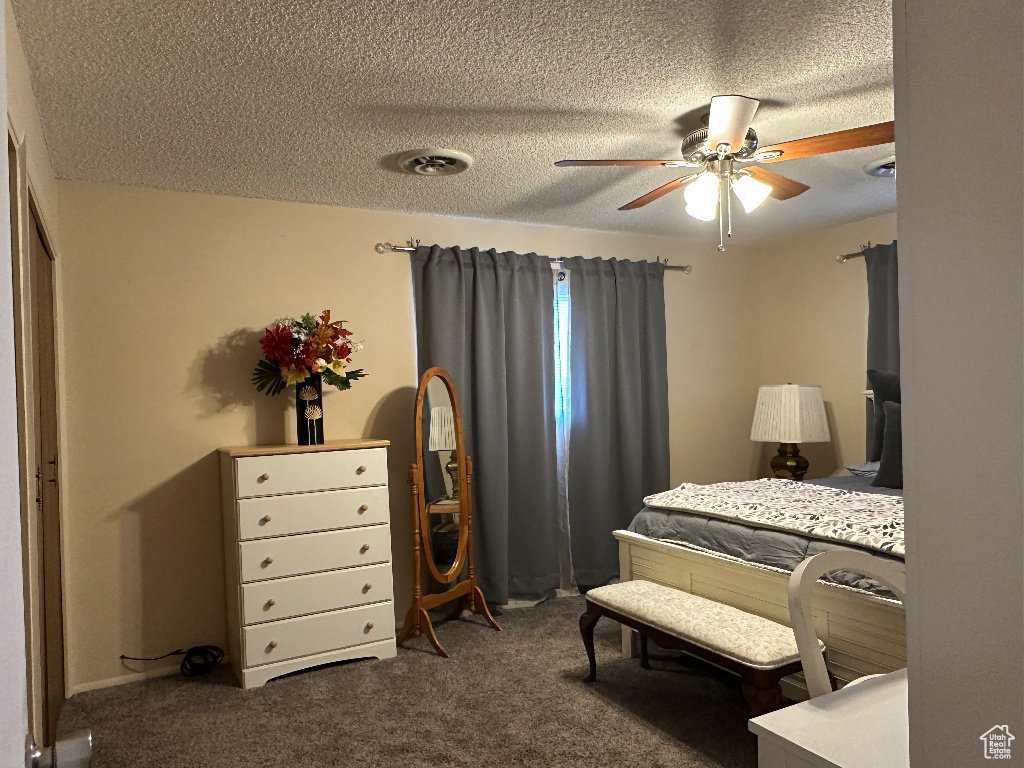 Bedroom with a textured ceiling, ceiling fan, and carpet