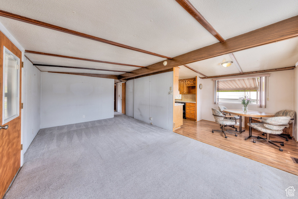 Interior space with beamed ceiling, a textured ceiling, and light colored carpet