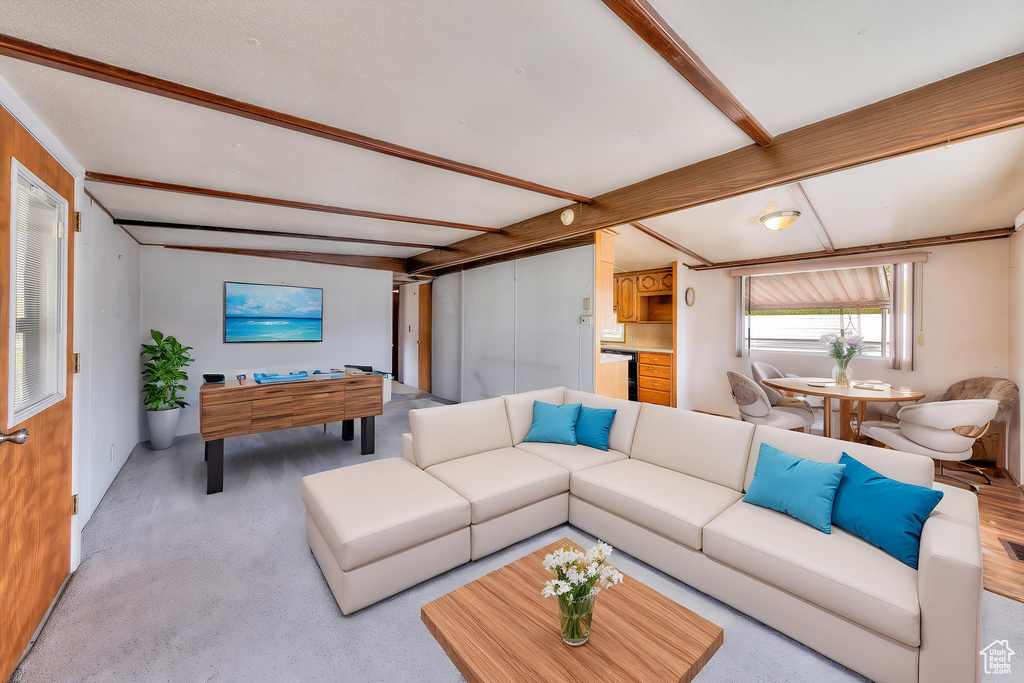 Carpeted living area featuring beamed ceiling