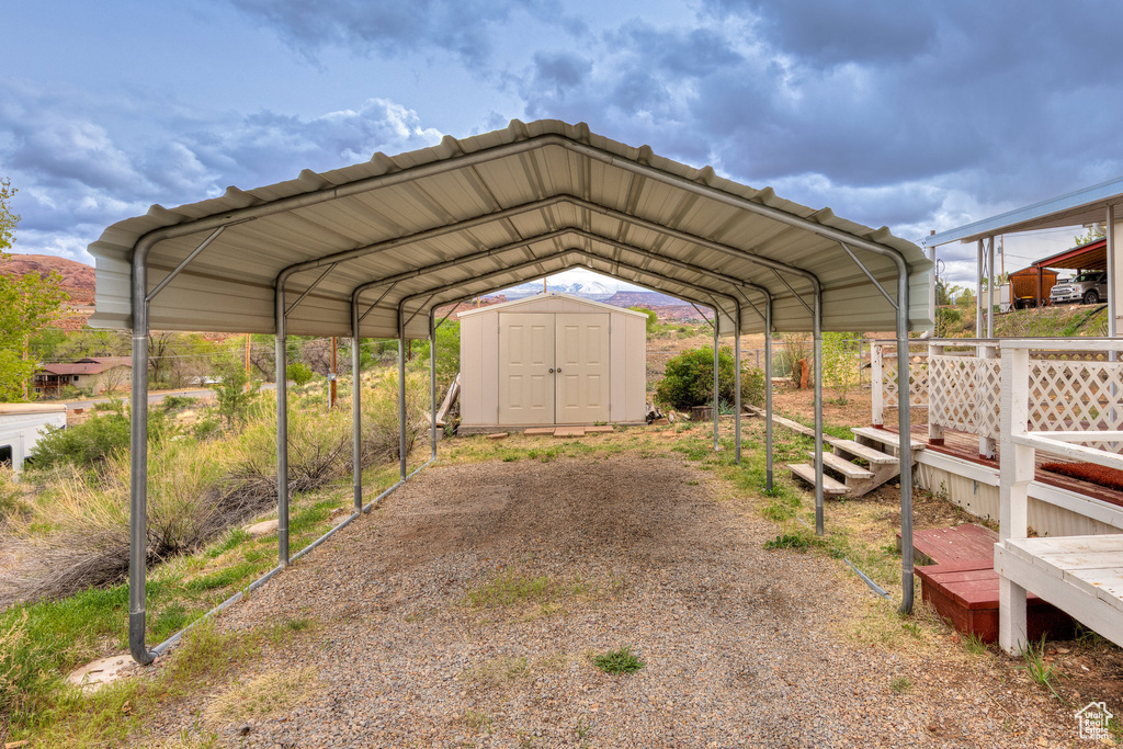 View of car parking featuring a storage unit and a detached carport