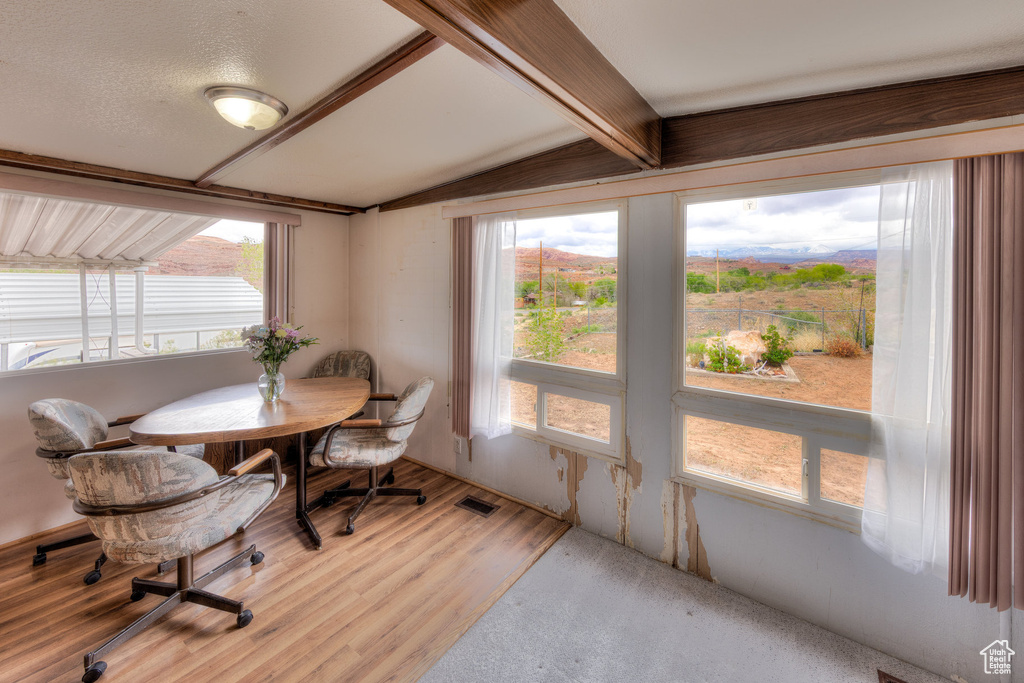 Dining area featuring light wood-style floors, plenty of natural light, and lofted ceiling with beams