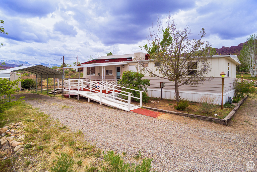 Rear view of house featuring covered porch, driveway, and a detached carport