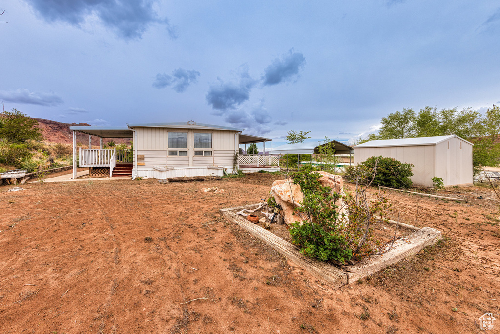 Rear view of property with fence, a wooden deck, and an outdoor structure