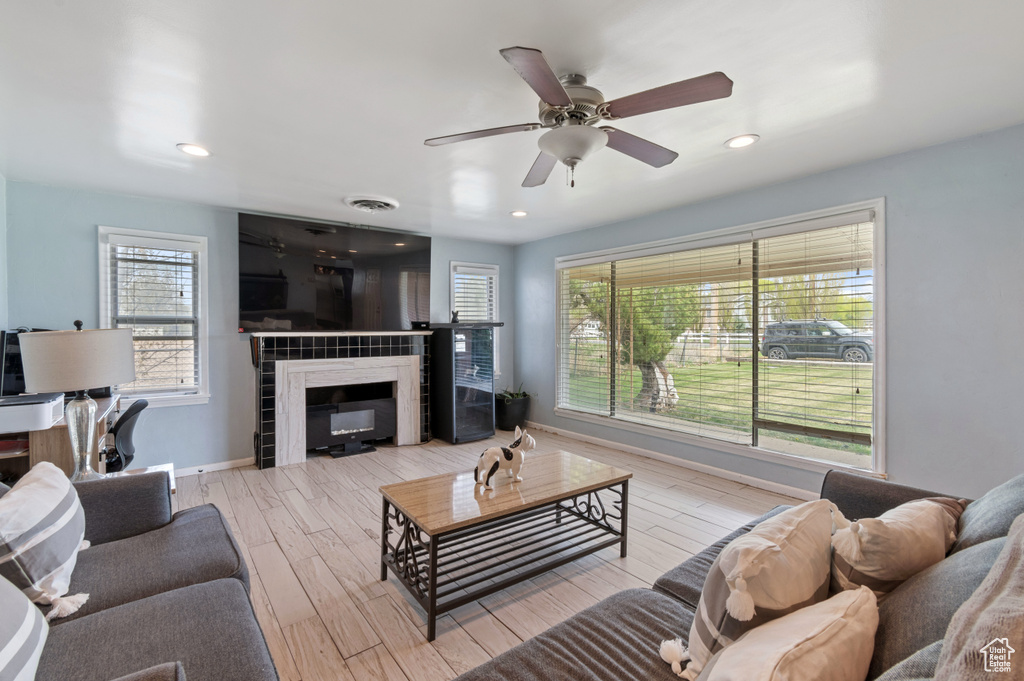 Living area with a tiled fireplace, recessed lighting, wood finished floors, baseboards, and a ceiling fan