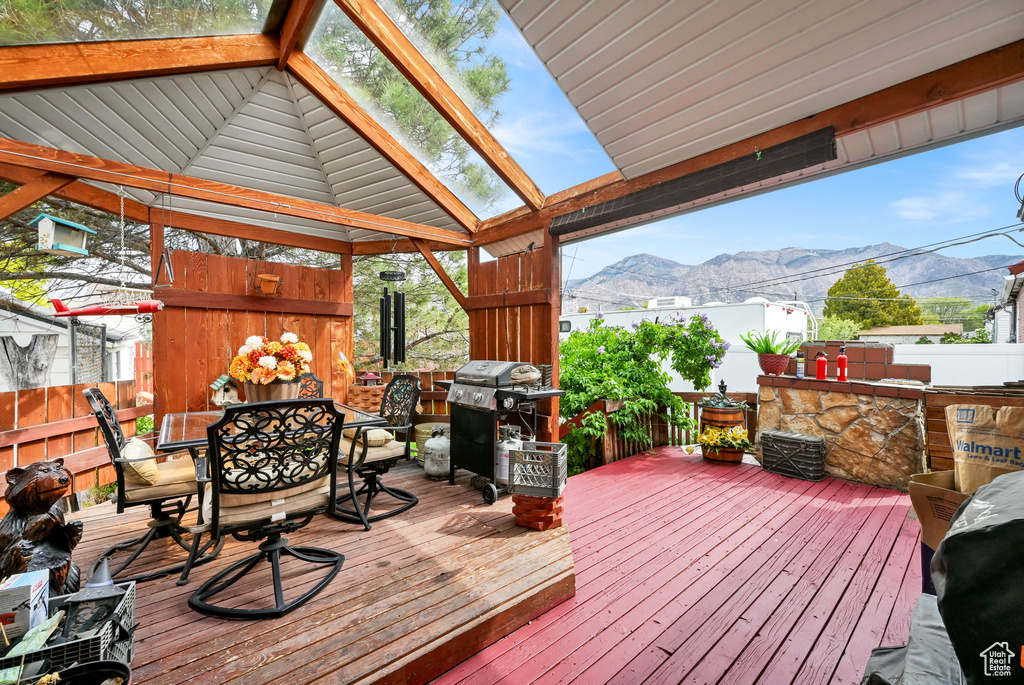 Wooden deck featuring fence, outdoor dining space, area for grilling, and a mountain view