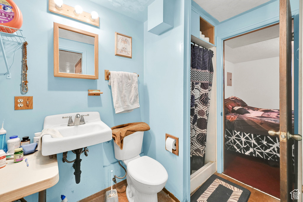 Bathroom with a stall shower, toilet, wood finished floors, and a sink