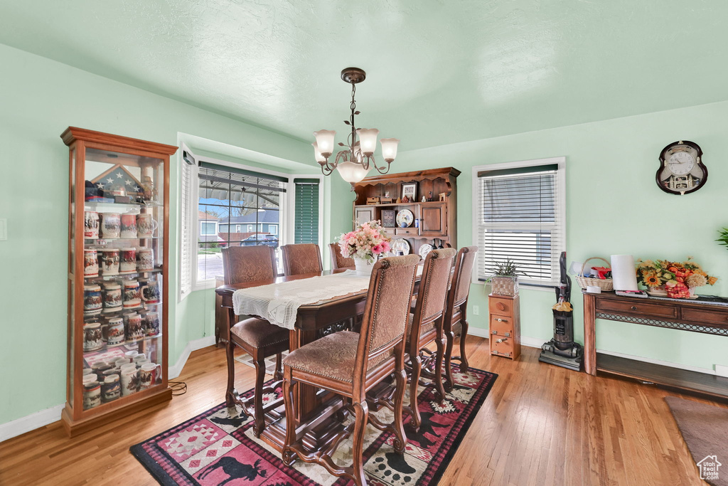 Dining space featuring baseboards, an inviting chandelier, and light wood-style flooring