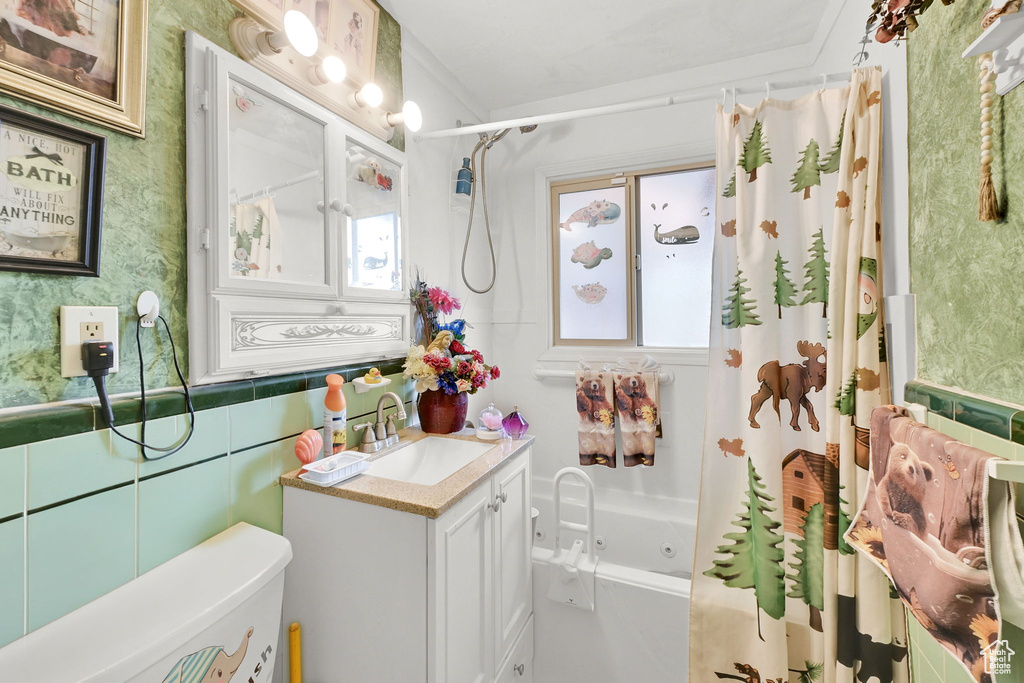 Bathroom featuring a wainscoted wall, wallpapered walls, shower / bath combo with shower curtain, toilet, and vanity