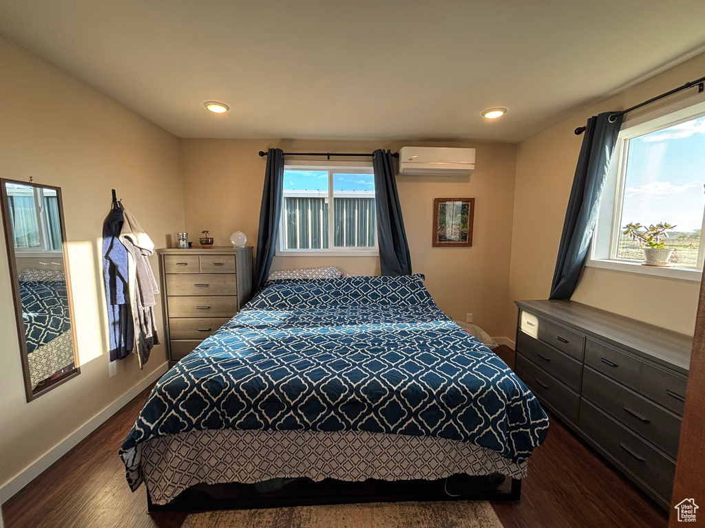 Bedroom with a wall mounted air conditioner, recessed lighting, baseboards, and dark wood finished floors