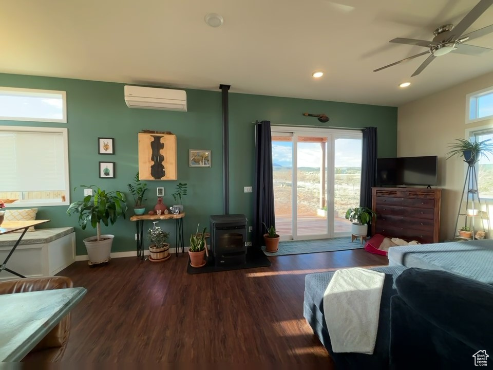 Bedroom featuring recessed lighting, wood finished floors, access to exterior, baseboards, and a wood stove