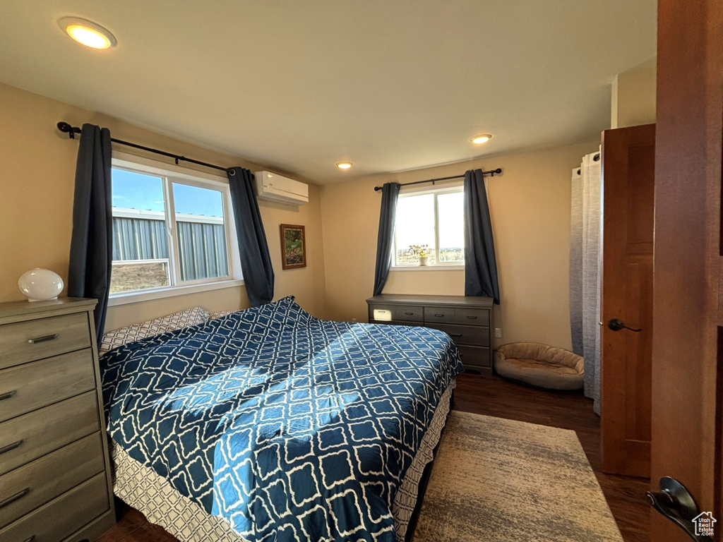 Bedroom featuring recessed lighting, an AC wall unit, and dark wood-type flooring