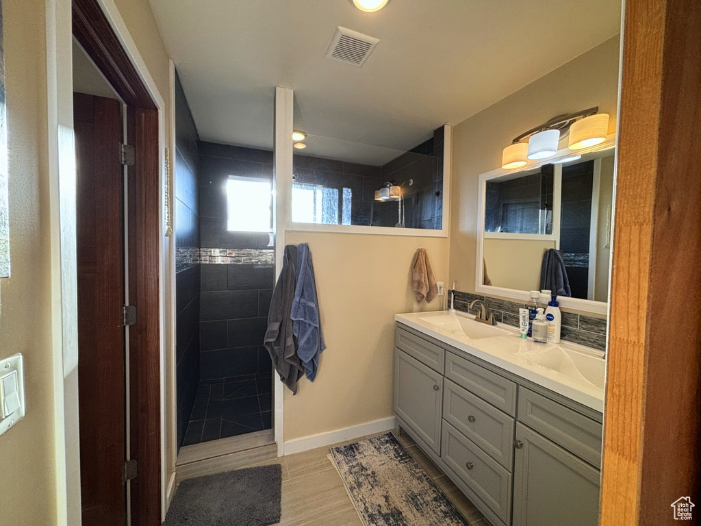 Full bathroom with a walk in shower, double vanity, a sink, baseboards, and visible vents