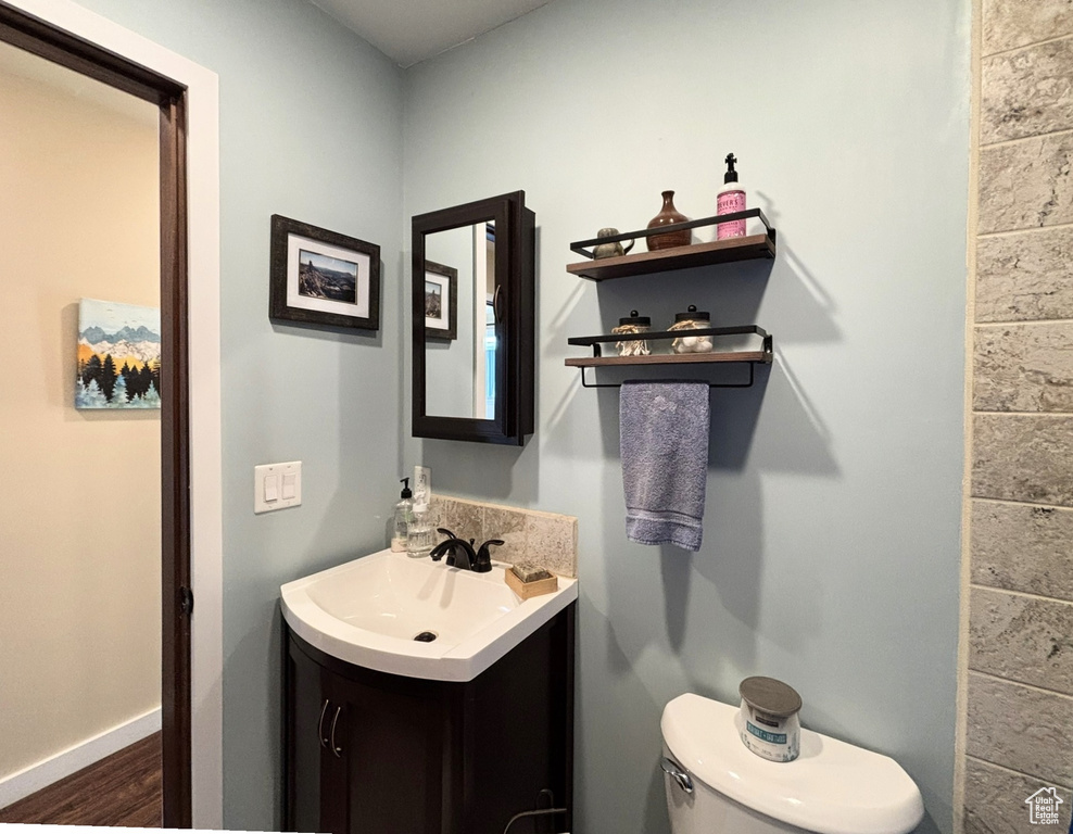 Bathroom with toilet, wood finished floors, vanity, and baseboards