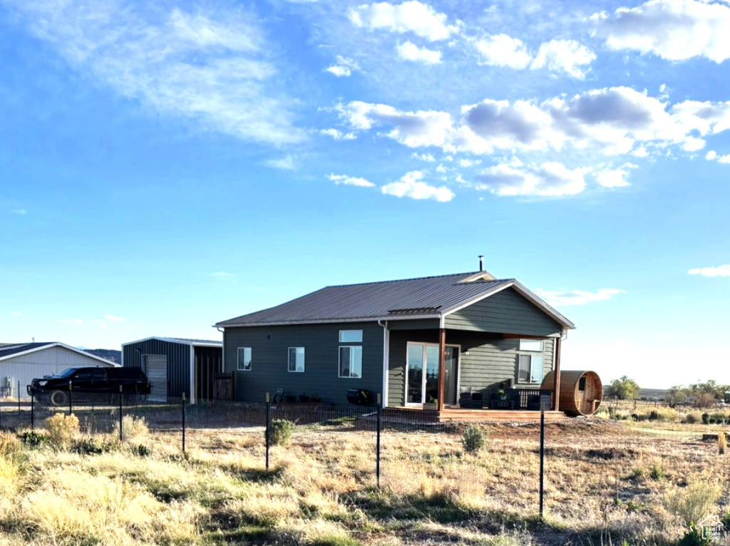 Rear view of house featuring a storage unit, fence, an outbuilding, and metal roof