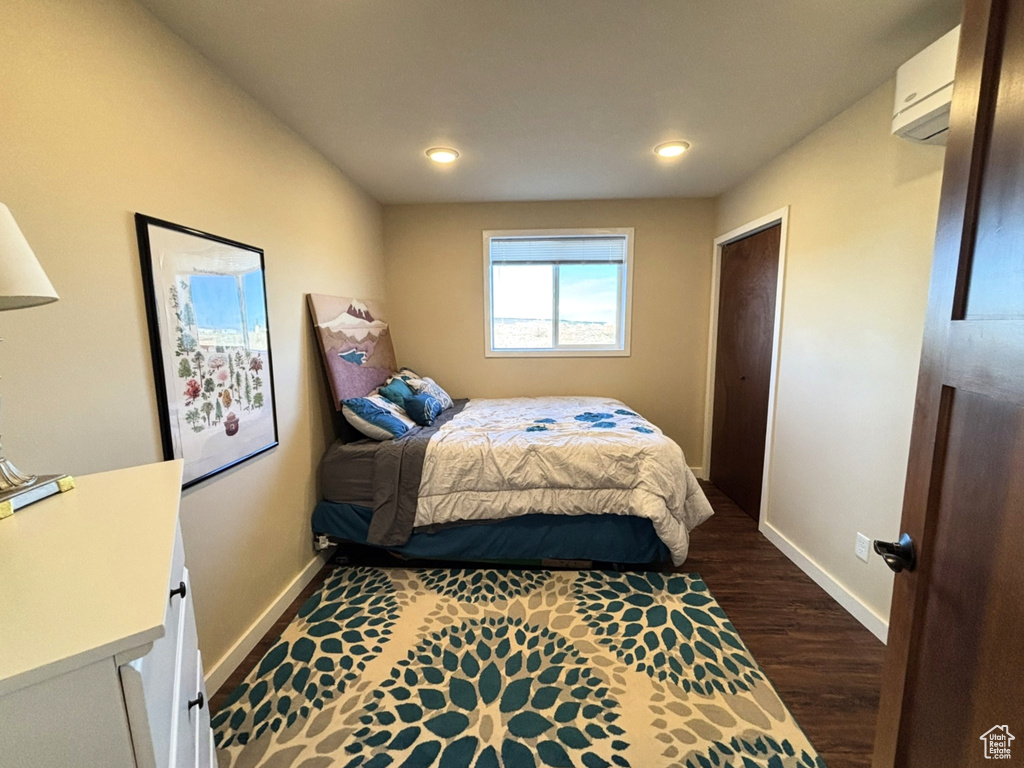Bedroom with dark wood-type flooring, recessed lighting, an AC wall unit, and baseboards