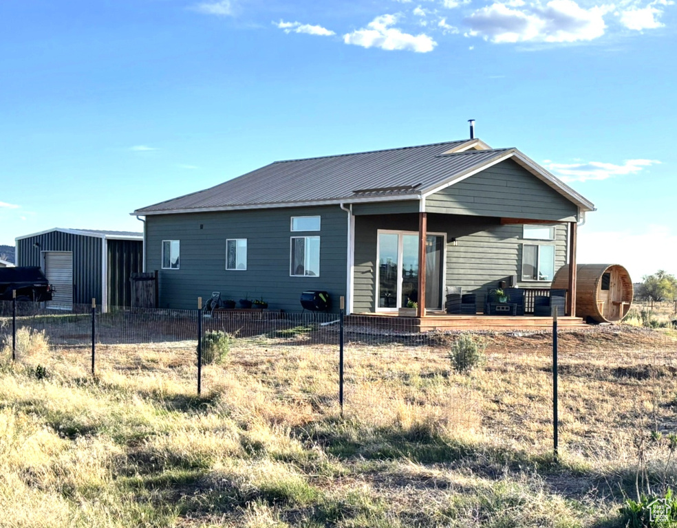 Back of property with an outdoor structure, metal roof, and fence
