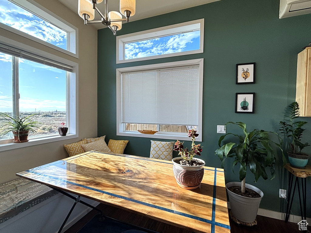 Dining space with a notable chandelier, a wall mounted AC, and baseboards