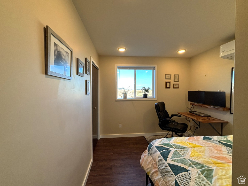 Bedroom with dark wood-type flooring, a wall mounted air conditioner, recessed lighting, and baseboards