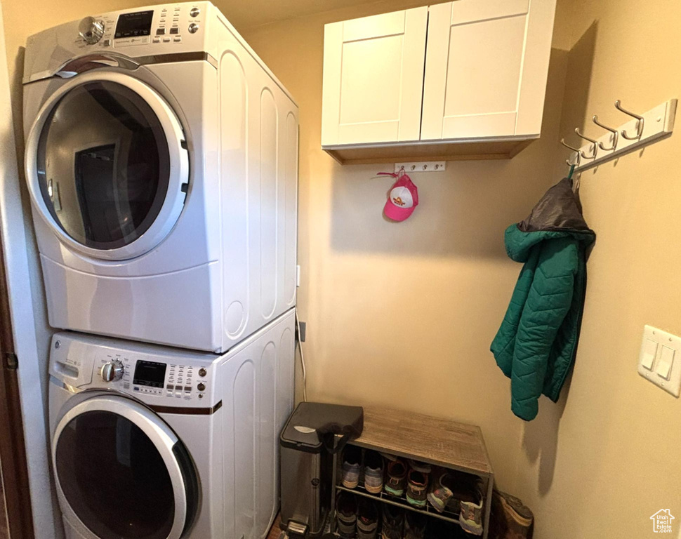 Laundry area featuring stacked washer / dryer and cabinet space