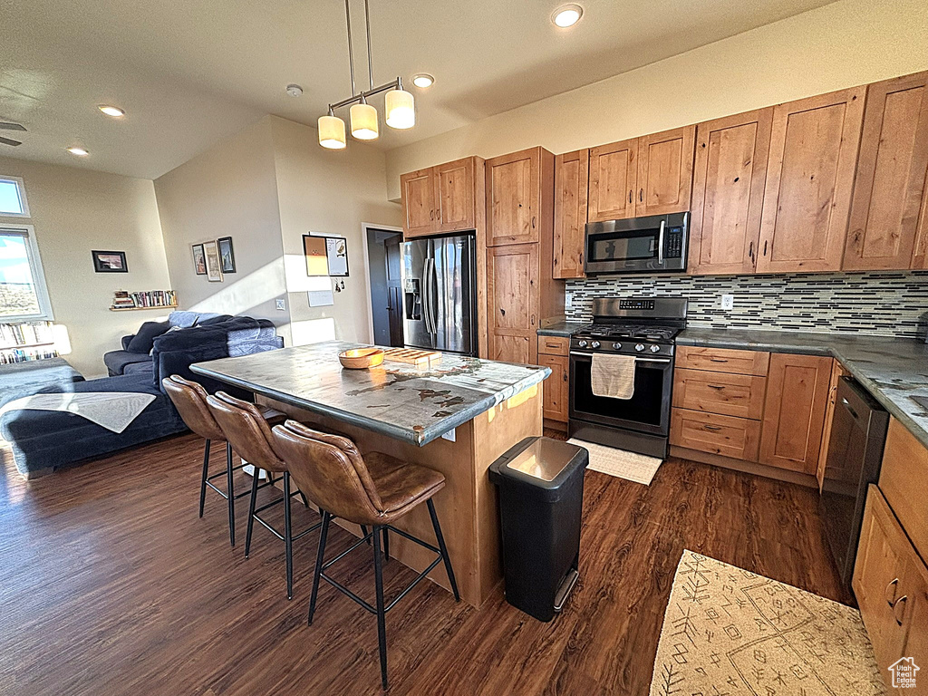 Kitchen with tasteful backsplash, dark countertops, stainless steel appliances, open floor plan, and dark wood-type flooring