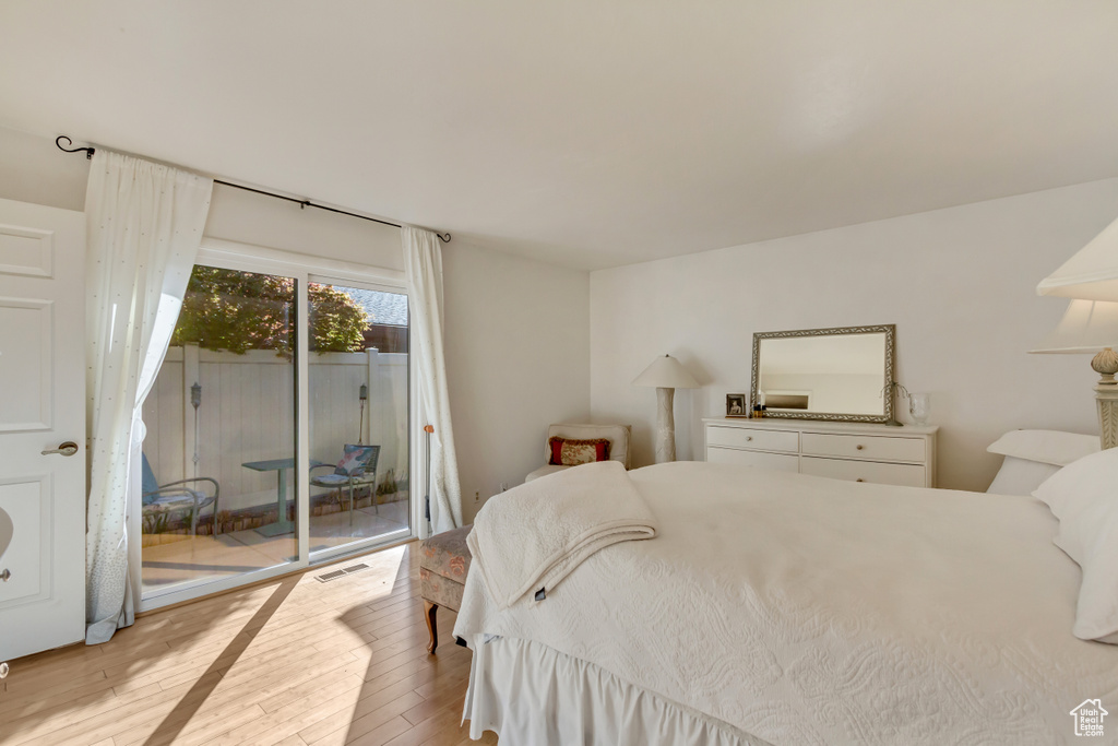 Bedroom with access to exterior, visible vents, and hardwood / wood-style floors
