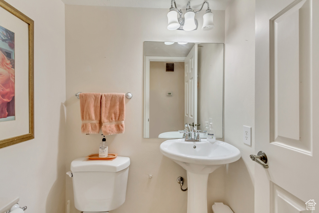 Half bathroom with toilet and a notable chandelier