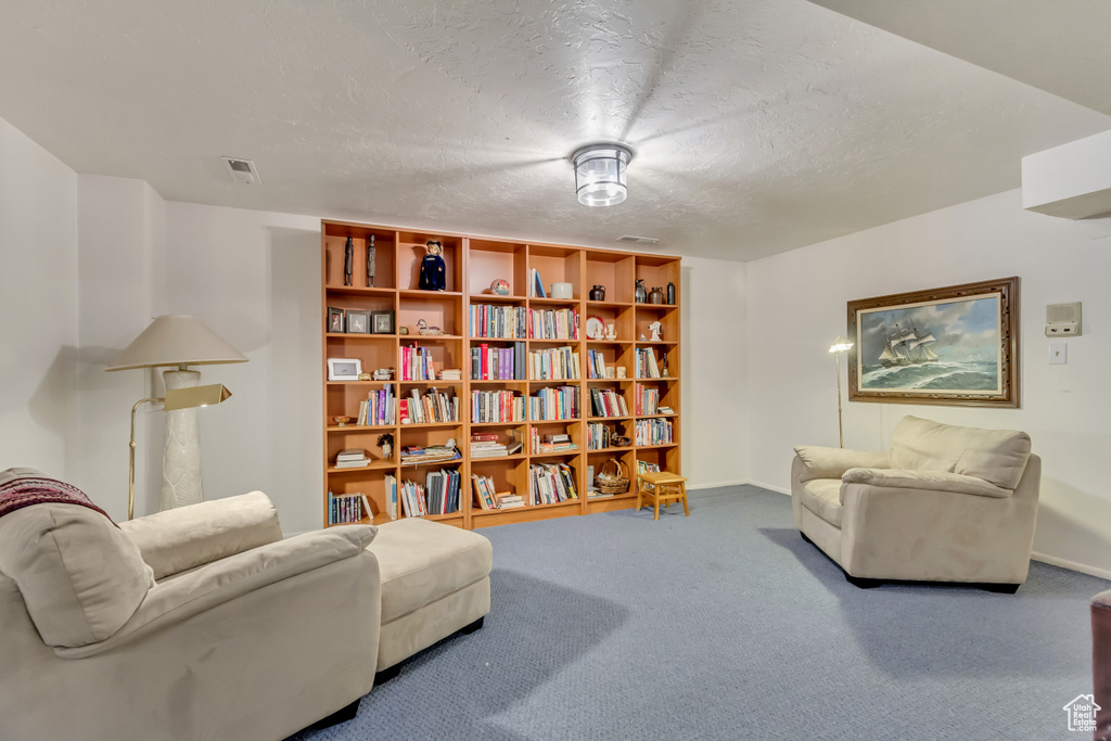 Living area with visible vents, baseboards, carpet, and a textured ceiling