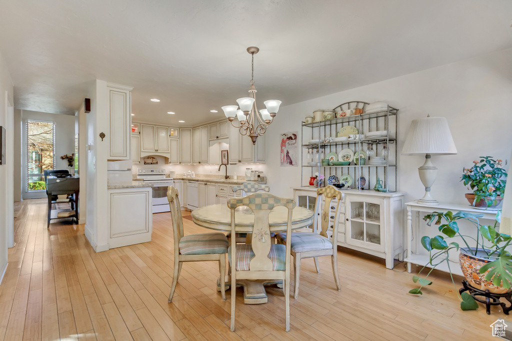 Dining room with recessed lighting, light wood finished floors, and an inviting chandelier