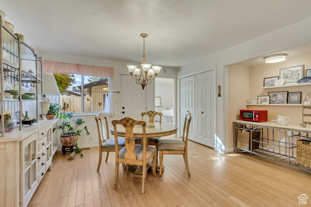 Dining area with light wood-type flooring, baseboards, and an inviting chandelier