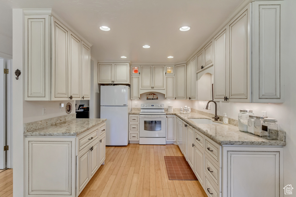 Kitchen featuring a sink, light wood-style floors, white appliances, light stone countertops, and recessed lighting