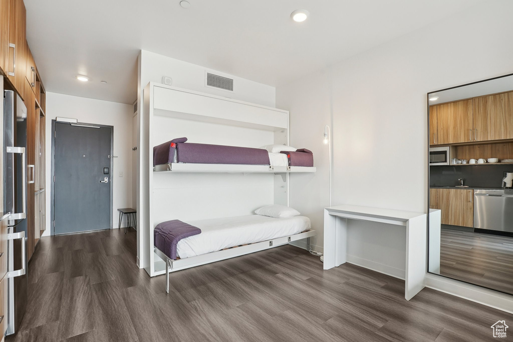 Bedroom with wood finished floors, recessed lighting, visible vents, and a sink